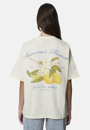 Osoba nosząca kremowy t-shirt z grafiką gałązki cytrynowej i białych kwiatów, z napisem "Summer Resort" oraz "Good For Nothing" na plecach.
