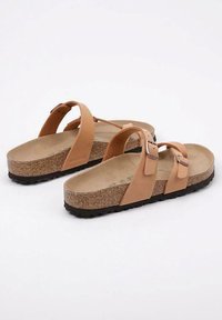 Tan cork sandals with two adjustable straps and a contoured footbed. Rubber sole for traction. Minimalist design with a flat profile.