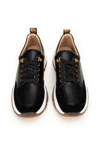 Czarne skórzane sneakersy z złotymi oczkami, sznurowany fason, białe boczne panele, teksturowane czarne akcenty i wzorzysty uchwyt na z tyłu.