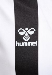 Czarno-biała materiał w paski z białym stylizowanym logo pszczoły i napisem „hummel” umieszczonym na środku czarnego paska.