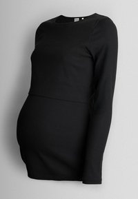 Cămașă de maternitate neagră, cu model cu nervuri, cu mâneci lungi, design ajustat, decolteu rotund și un panou care se adaptează unui burtica în creștere.