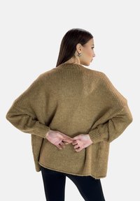 Maglione marrone sovradimensionato in maglia con texture a costine, spalle cadenti e maniche lunghe, caratterizzato da una vestibilità ampia e dettagli di orlo grezzo.