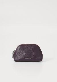 Porta monete in pelle viola intenso con finitura testurizzata, forma arrotondata, zip in argento e logo "COCCINELLE" impresso sulla parte anteriore.