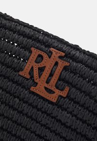 Svart flätad tote-väska med texturerad yta och en brun läderlogo som har bokstäverna "RL."