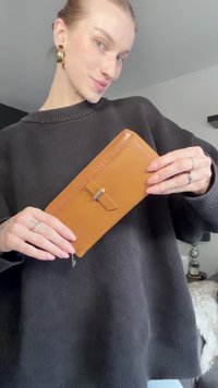 Kožená peněženka v tan barvě s texturovaným akcentem, vybavená malým klipem a zipovým uzávěrem. Design je elegantní s obdélníkovým tvarem.