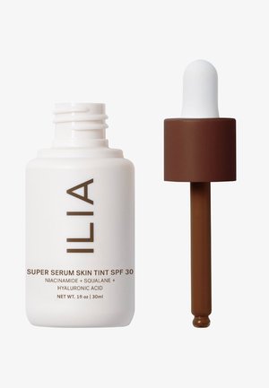 ILIA Super Serum Skin Tint SPF 30 w białej butelce z brązowym nadrukiem, z kroplomierzem z brązowym akcentem i białą bulwką. 30ml.