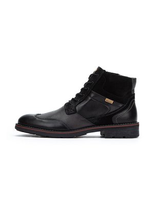 Botas negras hasta el tobillo con materiales mixtos: cuero liso y ante texturizado. Presentan un diseño con cordones, acentos cosidos y suela de goma.
