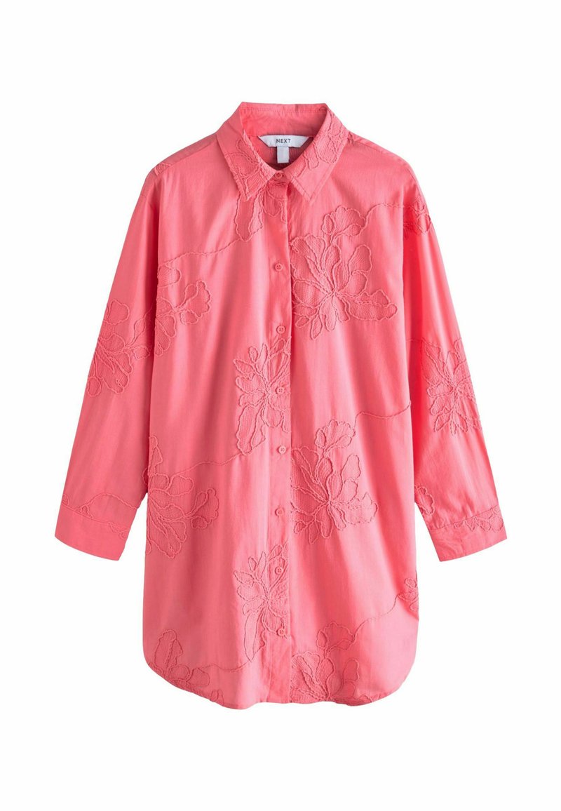 Camisa de color rosa coral con mangas largas y cuello, que presenta patrones florales bordados y un cierre frontal con botones. Textura de tela suave.