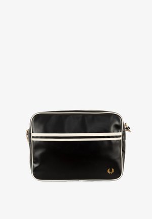 Bolsa mensajera sintética negra con franjas blancas, logo dorado, forma rectangular y una correa de hombro ajustable. Textura suave.