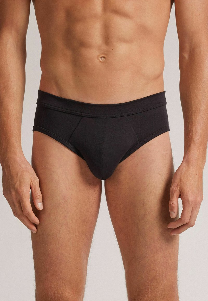 Schwarze Herrenunterhosen mit breitem Bund, glattem Stoff und taillierter Passform. Mit konturiertem Beutel und minimalen Nähten.
