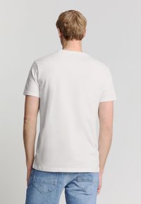 Witte katoenen t-shirt met korte mouwen, ronde halslijn en een eenvoudige achterzijde, gecombineerd met lichtblauwe denim jeans.