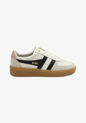 Sneaker bianca con strisce nere, suola in gomma e dettaglio rosa sul tallone. Presenta una chiusura con lacci e materiali in suede e pelle texturizzata.