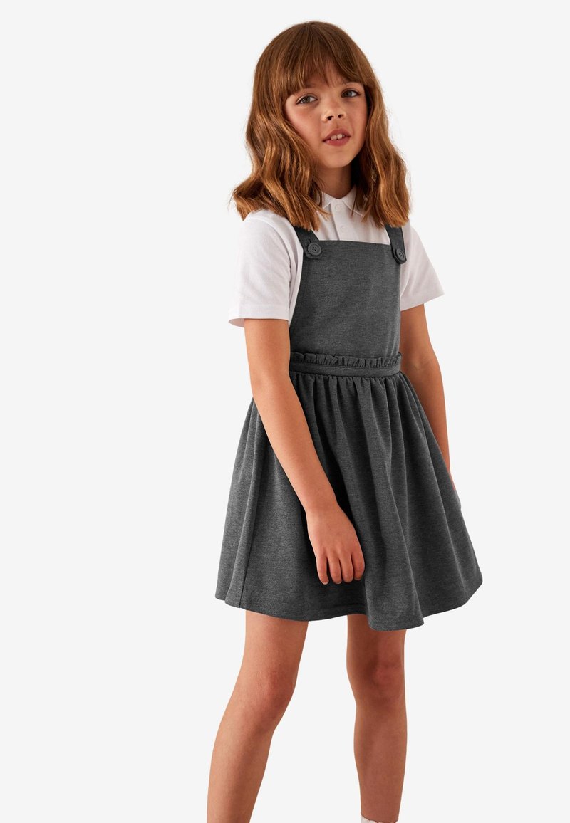 Gray cotton dress with a flared skirt and adjustable straps, featuring two button accents and a gathered waistline. White collared shirt underneath.