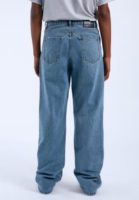 Lichtblauwe wijde jeans met hoge taille en een vijf-pocket ontwerp. Bevat vervaagde denimtextuur en een label op de achterkant van de tailleband.