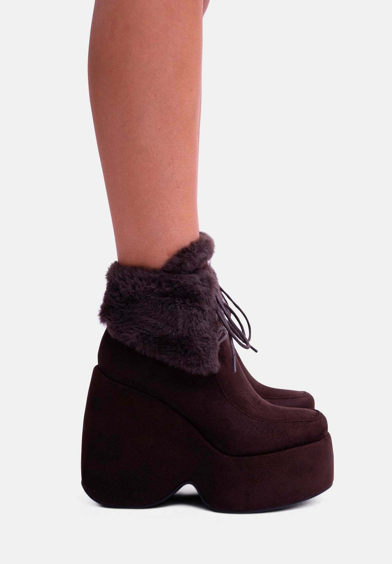 Stivali platform marrone scuro con un morbido risvolto in pelliccia sintetica, punta arrotondata e un distintivo tacco a forma di cuneo; design con lacci.