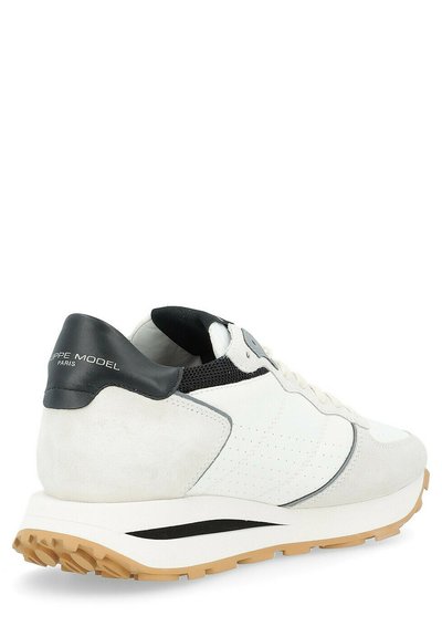 Sneaker bianca con accenti in suede e rete, linguetta nera sul tallone, dettagli perforati e suola in gomma testurizzata. Presenta un design minimalista.