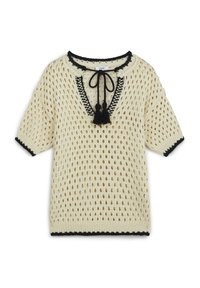 Crème gebreid pullover met open gaasontwerp, zwarte rand rond de halslijn en mouwen, en decoratieve kwastjes bij de halslijn.