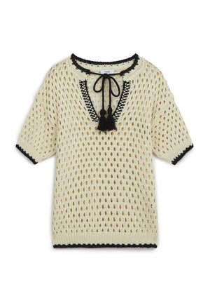 Crème gebreid pullover met open gaasontwerp, zwarte rand rond de halslijn en mouwen, en decoratieve kwastjes bij de halslijn.