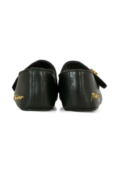 Czarne skórzane buty o gładkiej fakturze, z złotymi akcentami, tylnym paskiem i minimalistycznym wzornictwem. Nazwa marki jest wyszyta na złoto.