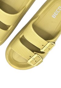 Gele plastic sandalen met twee verstelbare gespsluitingen, gestructureerde zijkanten en een holle voetbed voor ademend vermogen.