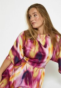 Fließendes Kleid mit lebhaftem, abstraktem Muster in Pink, Gelb und Lila; verfügt über Ärmel in Elbow-Länge und einen gebundenen Taillengürtel für eine anpassbare Passform.