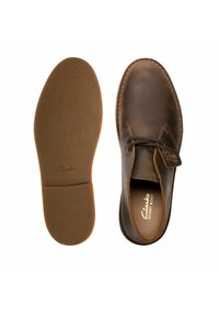 Ruskeat nahkaiset Clarks Desert -saappaat, joissa on pyöreä kärki, ommeltuja yksityiskohtia ja kumipohja. Mukana brändätty pohjallinen, jossa on teksturoitu pohja.