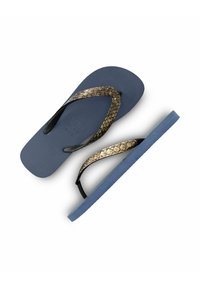 Des tongs bleues avec une semelle en caoutchouc texturée, présentant une bride en imitation serpent dorée et des accents noirs sur les brides.