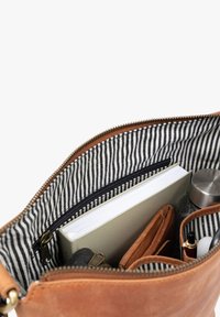 Braunes Lederinnentasche mit gestreiftem Stofffutter, ausgestattet mit einem Notizbuch, einer Wasserflasche und Organisationsfächern für Zubehör.