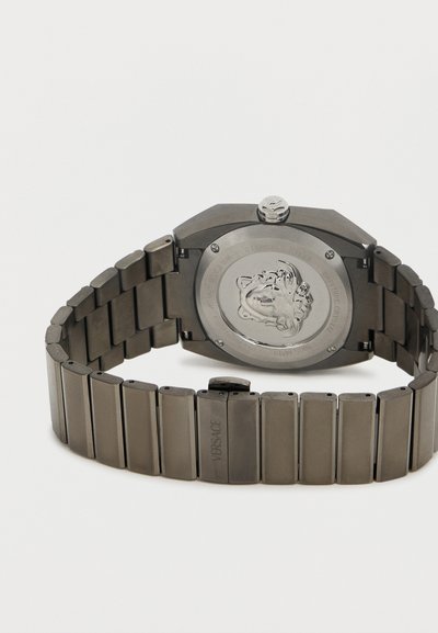 Ρολόι χειρός από ατσάλι σε ασημί απόχρωση με μπρασελέ από κρίκους, που διαθέτει ανάγλυφο έμβλημα της Μέδουσας στο πίσω μέρος και την επιγραφή "Versace" στη πόρπη.