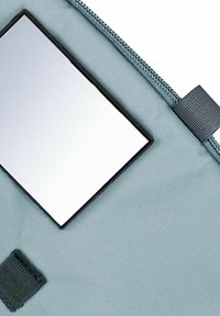 Bolsa con cremallera de tela azul claro con un espejo rectangular incrustado. Presenta una superficie texturizada y un acento de tela negra cerca de la cremallera.