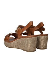 Braune Leder Wedgesandalen mit gewebtem Jute-Plateau, ausgestattet mit einem breiten Riemen und metallischen Schnallenakzenten. Strukturierte Oberfläche auf dem Wedge.