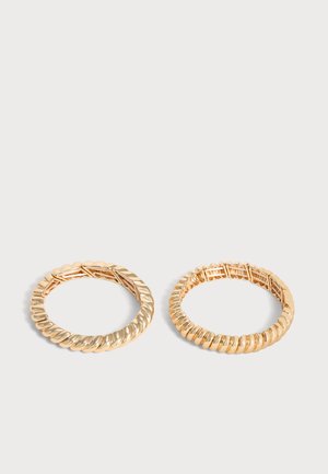 Two gold hoop earrings with textured, twisted and ridged designs, displayed on a plain light background.