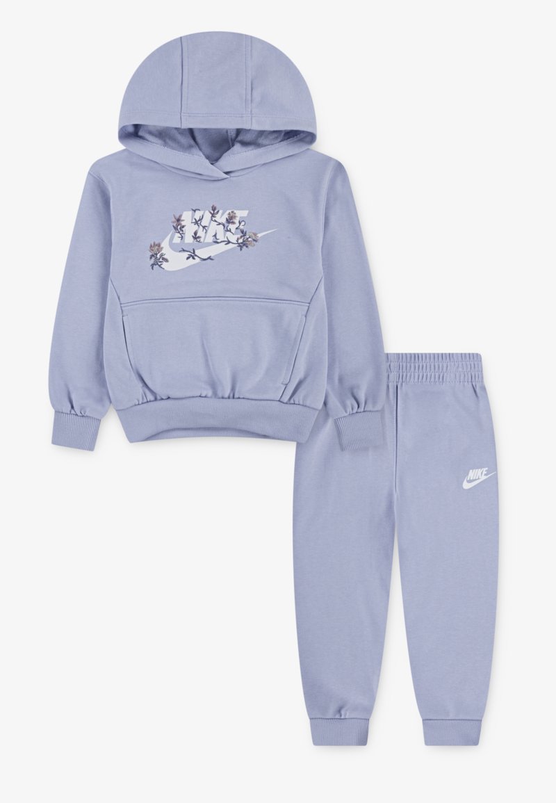 Φωτεινό μωβ αθλητικό σετ που περιλαμβάνει μια κουκούλα με λουλούδια στο λογότυπο Nike και αντίστοιχες φόρμες με ελαστική μέση και λογότυπο Nike. Μαλακή υφή υφάσματος.