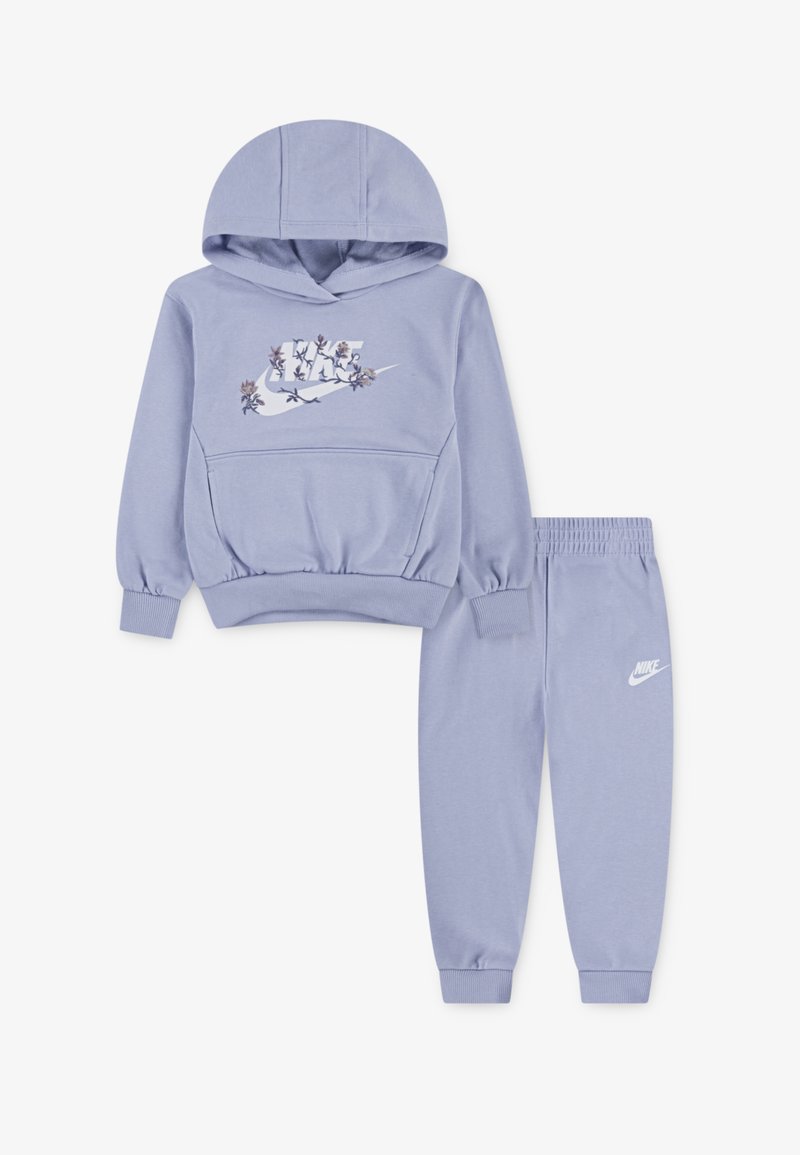 Hellblauer Trainingsanzug mit Kapuze, der das florale Nike-Logo zeigt, sowie passenden Sweatpants mit elastischem Bund und Nike-Logo. Weiches Material.