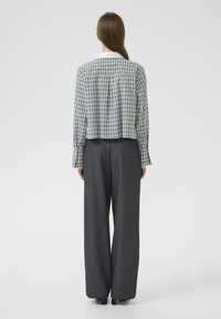 Camisa de cuadros en azul y verde con cuello blanco; combinada con pantalones de pierna ancha grises de cintura alta; textura suave.