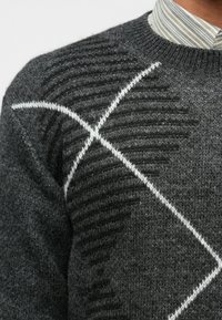 Σκούρο γκρι πουλόβερ από υφασμάτινη πλέξη με υφή, που διαθέτει σχέδιο λευκής διαγωνίου γραμμής και ριγέ γιακά από κάτω.