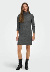 Robe en maille grise à col roulé avec manches longues et ourlet côtelé, associée à des bottines noires. Texture lisse, silhouette ajustée.