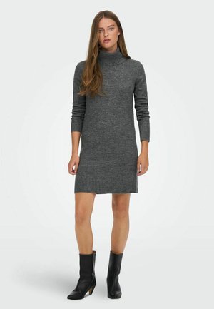 Robe en maille grise à col roulé avec manches longues et ourlet côtelé, associée à des bottines noires. Texture lisse, silhouette ajustée.