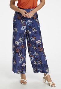 Wijdvallende broek van een blauwe stof met een bloemenprint in rood, wit en donkerblauw. Inclusief zijzakken en een relaxed pasvorm.
