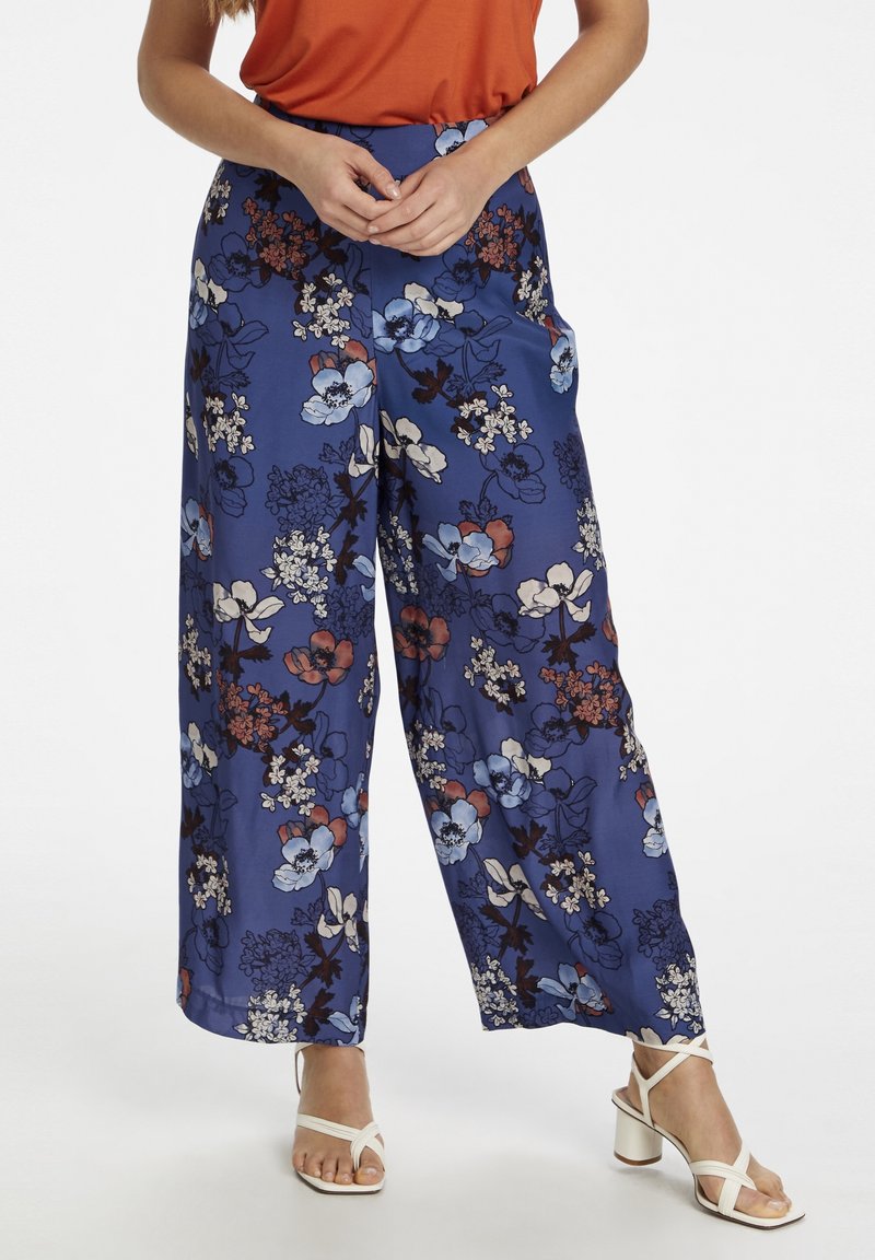 Wijdvallende broek van een blauwe stof met een bloemenprint in rood, wit en donkerblauw. Inclusief zijzakken en een relaxed pasvorm.