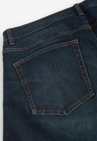 Spijkerbroek in een donkere wassing, met een achterzak voorzien van oranje stiksels. Glad textuur, traditionele vijf-pocket ontwerp.