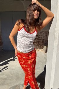White floral print tank top with red accents; red floral skirt, smooth texture; casual, layered design. Outdoor setting with natural light.