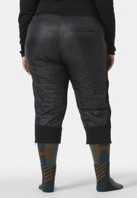 Zwarte gepolsterde sportbroek met gestructureerde panelen, cropped ontwerp en een elastische tailleband. Gekocht met teal en gouden patroon sokken.