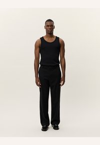 Black tank top made of a smooth, stretchy fabric, paired with black wide-leg trousers. The outfit features a simple design and relaxed fit.