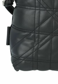 Sac en cuir noir avec un motif matelassé, présentant des coutures diagonales, une texture douce et une courte bandoulière attachée d'un côté.