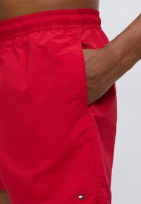 Κόκκινα μαγιό σορτς από ελαφρύ ύφασμα, με ελαστική μέση, πλαϊνή τσέπη και μικρό λογότυπο στο τελείωμα.