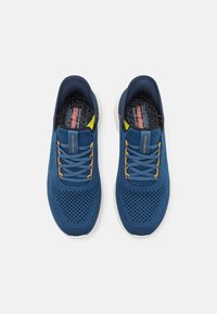 Niebieskie siateczkowe sneakersy z pomarańczowymi akcentami, odblaskowymi detalami i lekką białą podeszwą. Posiadają sznurowane zapięcie i teksturowaną cholewkę.