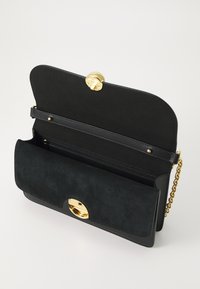 Borsa a mano in pelle nera con dettagli in oro, scomparto con zip e texture in suede. Include una tracolla a catena e una chiusura a pulsante.