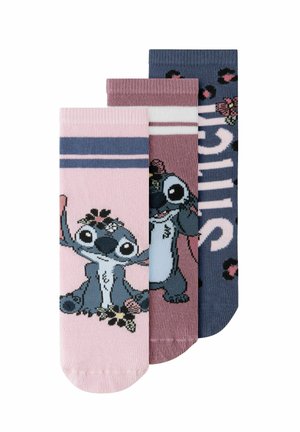 Trois chaussettes colorées pour enfants avec le personnage de dessin animé Stitch et des détails floraux, en rose, mauve et bleu marine.