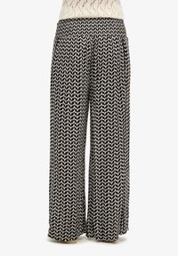 Pantalones de pierna ancha hechos de un tejido ligero, con un patrón geométrico en blanco y negro, cinturilla elástica y caída fluida.